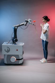 A robot arm presents a flower to a smiling woman, illustrating human-robot interaction.